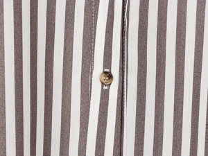 Detail of linen blend vertical stripes and a dark brown button on the shirt front