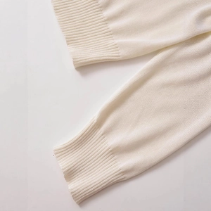Close-up of white knit cardigan showing ribbed cuffs and fine needlework texture
