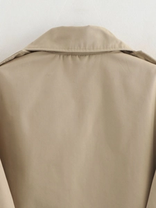Detailed view of khaki trench coat neckline featuring epaulettes and twill fabric texture