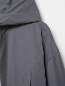 Detail of dark grey hooded jacket fabric with twill texture and cross-stitch pockets