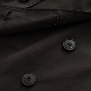Detail of double-breasted buttons with marble texture on black cropped trench coat