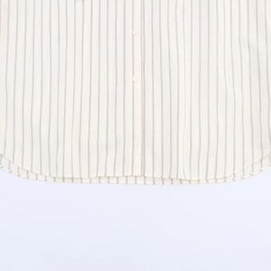 Détail de l'ourlet arrondi et des coutures d'une chemise rayée boutonnée ample