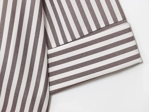 Detailed close-up of striped linen blend shirt sleeve with precise stitching and fabric texture