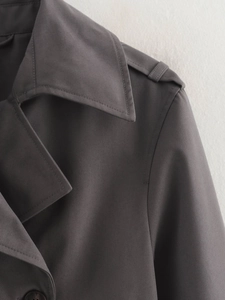 Detail of dark grey short trench coat showing twill fabric texture and shoulder epaulets