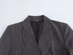 Detailed view of structured shoulder pads and textured weave on grey blazer lapel