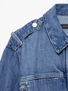 Detail of washed blue denim jacket featuring shoulder epaulets and metallic buttons
