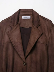 Détail d'une veste en suédine avec col à revers, coutures et fermeture à bouton noir