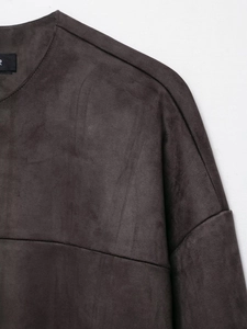 Detail of the crew neck and dropped shoulder seams on a charcoal gray faux suede jacket