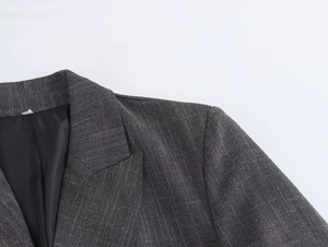 Close-up of dark grey blazer lapel and shoulder pads showing premium woven fabric texture