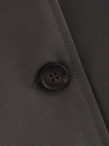 Close-up of charcoal grey twill coat with brown four-hole button and premium stitching