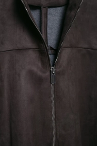 Close-up of a dark brown suede jacket showing zipper detail and gray knitted lining