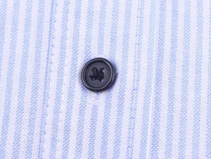 Detailed macro view of blue and white striped poplin fabric with a dark four-hole button
