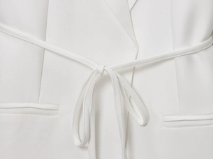 Détail d'un blazer blanc en lin mélangé avec ceinture nouée et revers à pointes