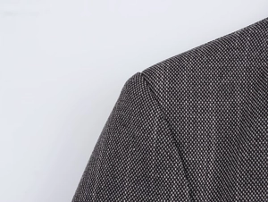 Detailed macro shot of the shoulder seam and padding on this dark grey blazer jacket