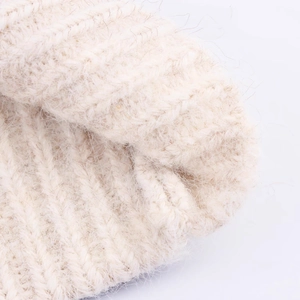 Close-up of cream chunky knit sweater fabric with fuzzy texture and warm wool fibers