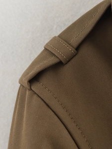 Macro shot of trench coat shoulder epaulettes with double-row stitching and twill texture