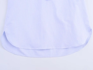 Detail of light blue striped cotton shirt featuring a curved hem and side slit design