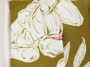 Close-up of olive green linen fabric featuring white floral patterns and detailed stitching