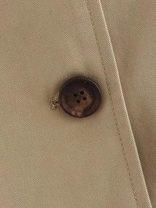Macro view of brown tortoiseshell button and premium twill fabric on khaki trench coat