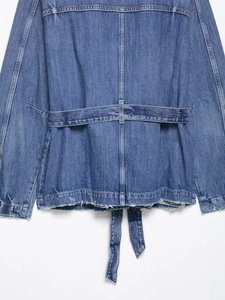 Detail view of denim jacket back featuring a raw hem and adjustable waist strap