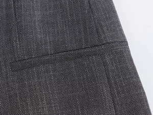 Detail of dark gray blend fabric showing precise stitching on blazer pocket and seam