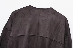 Macro detail of dark brown faux suede jacket featuring back cross stitching and smooth texture