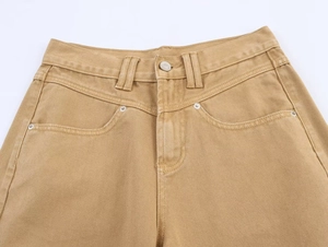 Close-up of khaki denim texture with metallic button and reinforced pocket rivets