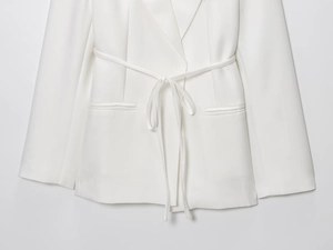 Détails d'un blazer blanc en lin avec ceinture nouée et poches passepoilées