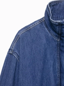 Detailed close-up of dark blue denim jacket neckline with contrast orange stitching