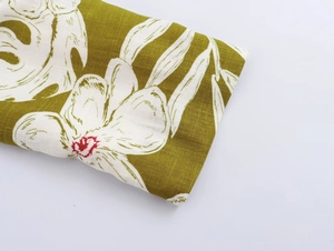 Macro detail of olive green linen fabric featuring tropical floral prints and stitching