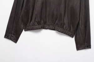 Detail of the elastic hem and adjustable metal button cuffs on a dark brown suede jacket