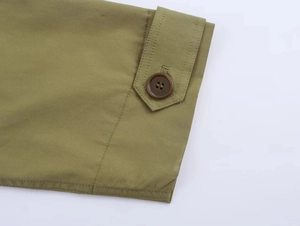 Detail of olive green jacket cuff with textured twill fabric and brown button closure