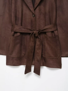 Détail d'une veste en daim marron foncé avec ceinture et grandes poches plaquées