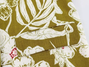 Detailed close-up of linen blend blazer pocket with white floral prints on olive green fabric