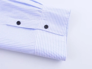 Close-up of blue striped poplin shirt cuffs with polished black buttons and fine stitching