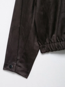 Detail of dark brown faux suede jacket sleeve with round metal snap button and elastic hem