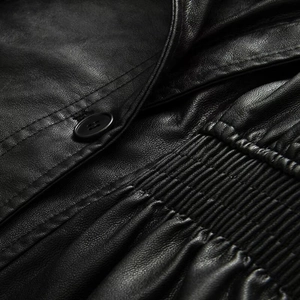 Close-up detail of black leather jacket with elastic smocking and round button fastening