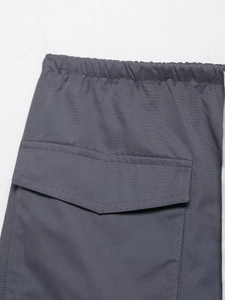 Detail of dark grey cargo shorts featuring elastic waistband and flap pocket stitching