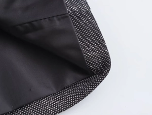 Close-up of black and white woven blazer fabric with smooth inner lining and stitching
