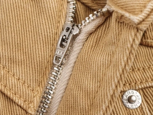 Detailed macro view of high-quality YKK zipper and metal JEANS button on khaki denim pants
