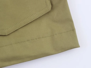 Detail of army green parka showing high-quality twill fabric and reinforced pocket stitching