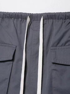 Detailed close-up of dark grey cargo pants featuring elastic waist and white drawstrings
