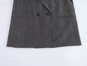 Detail of dark grey blazer showing double-breasted black buttons and flap pockets