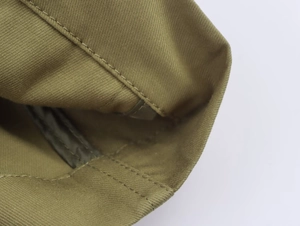 Close-up of olive green parka jacket featuring twill fabric and reinforced double stitching