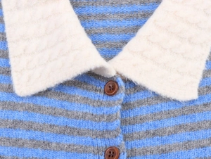 Detail of blue striped knit cardigan with plush cream collar and brown buttons