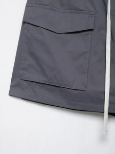 Detailed view of dark grey cargo shorts with large flap pocket and white drawstrings