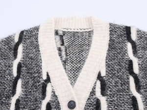 Détail macro du cardigan en maille noir et blanc montrant le col en V et le bouton