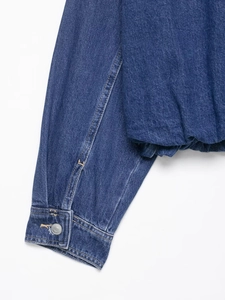 Close-up of dark blue denim jacket cuff with metal button and elastic hem details
