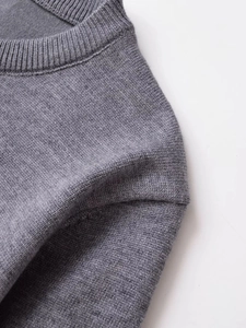 Close-up of the ribbed neckline and fine knit texture on the dark grey sweater