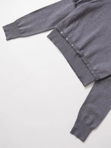 Detail view of grey knit sweater featuring delicate buttons and long ribbed cuffs texture